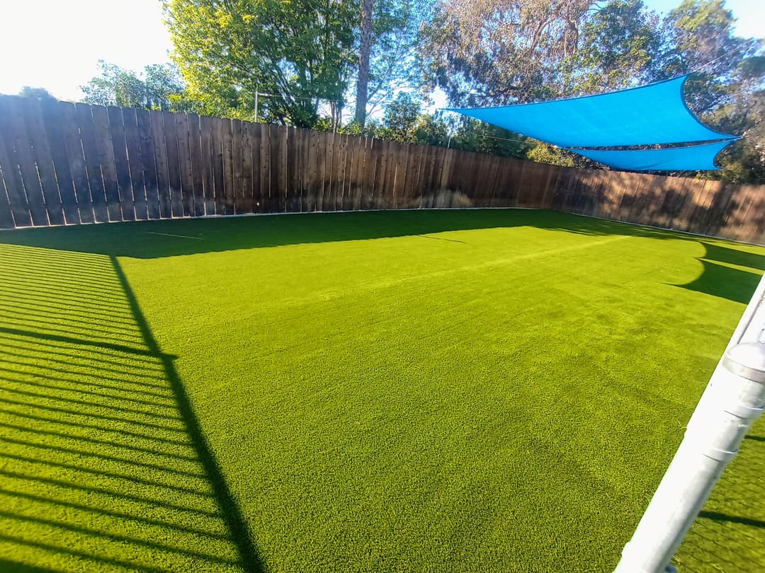 backyard with artificial turf and blue shade sail